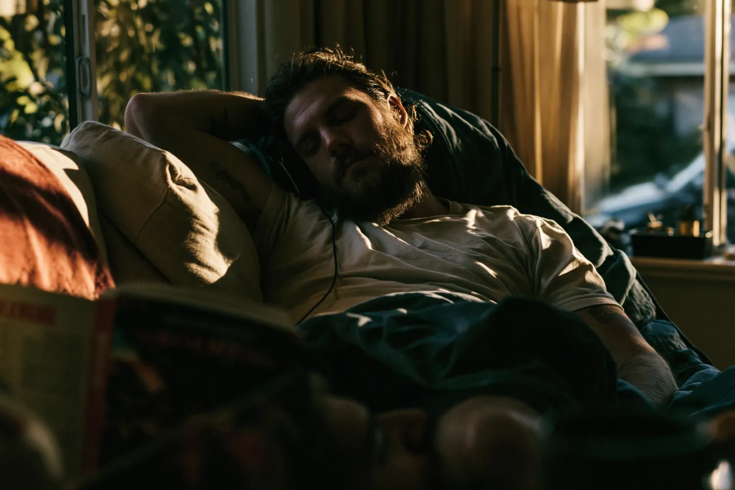A tired man resting on a couch in warm evening light